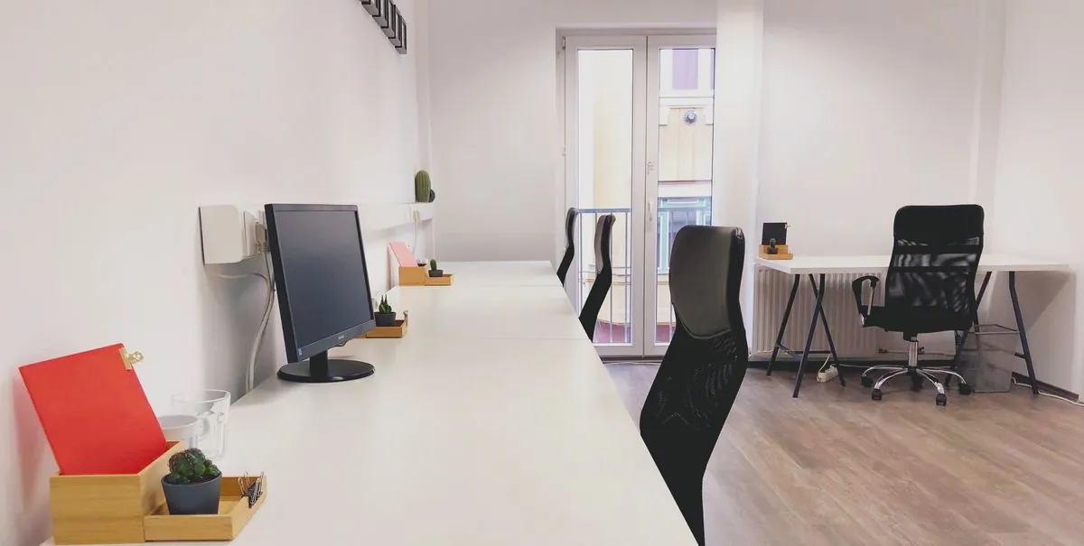 Espace de coworking lumineux et moderne, avec des postes de travail partagés et de grandes fenêtres