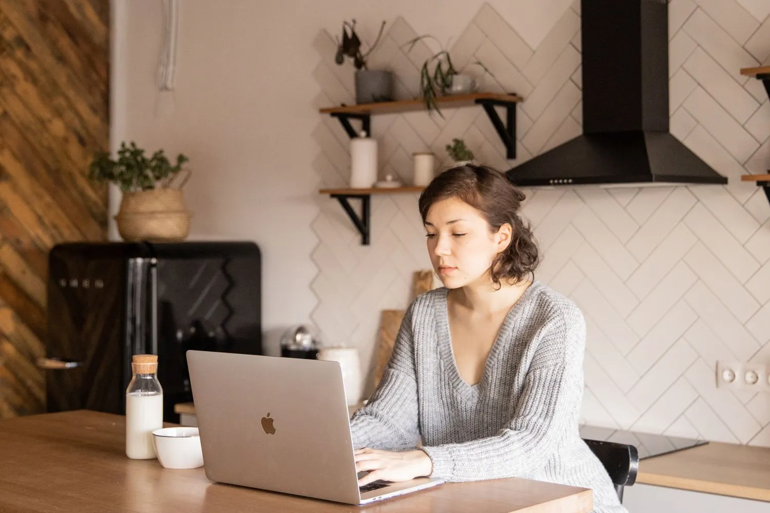 Jeune femme installée à son ordinateur portable dans le salon de son domicile, en pleine journée de travail
